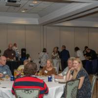 Guests sit at their tables in the celebration while others mingle in the background